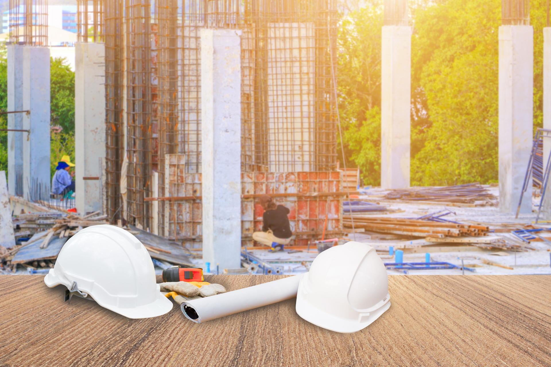 deux sécurité blanc casque et cuir Gant mètre-ruban, rouleau papier plan plan d’ingénierie travaillant au chantier de construction s’appuyant sur la table de plancher en bois avec espace copie ajouter du texte. arrière-plan flou